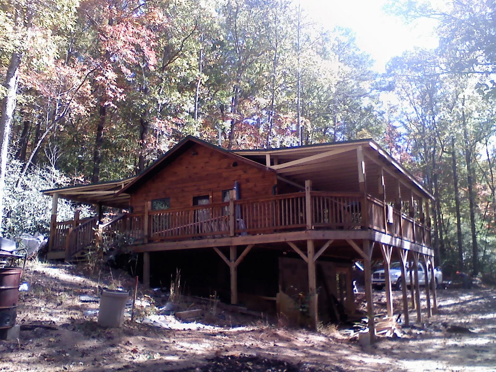 Log cabin with a wraparound porch and metal roof in the fall in Mill Hall
