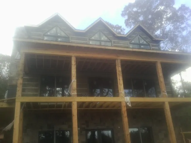 Dormers and porch framing on a large log home under construction — Roof Coating work by our crew in Mill Hall