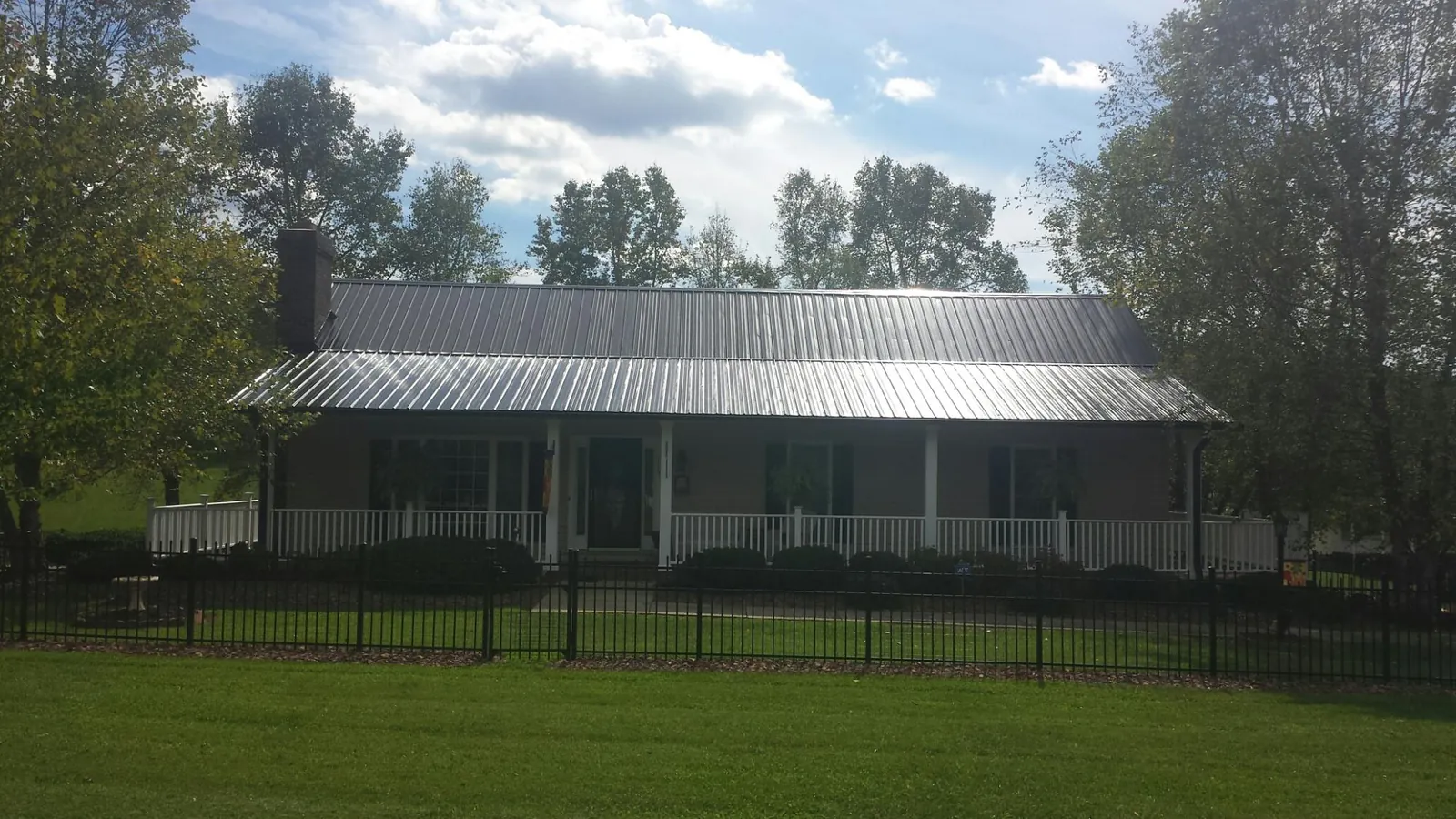 Gray metal roof on a brick ranch with a full width front porch — Gutter Guard Installation work by our crew in Mill Hall