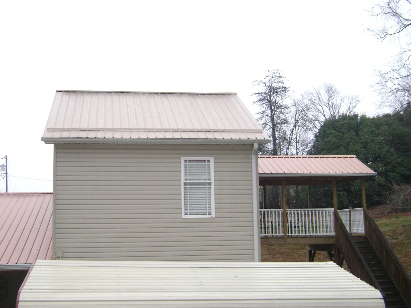 Tan metal roofs on a two story addition and attached porch, from a Roof Replacement job in Mill Hall